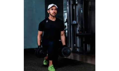 Guy holding a pair of dumbbells performs a set of walking lunges.