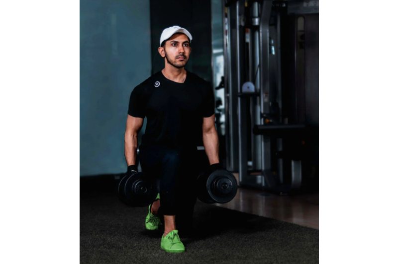Guy holding a pair of dumbbells performs a set of walking lunges.