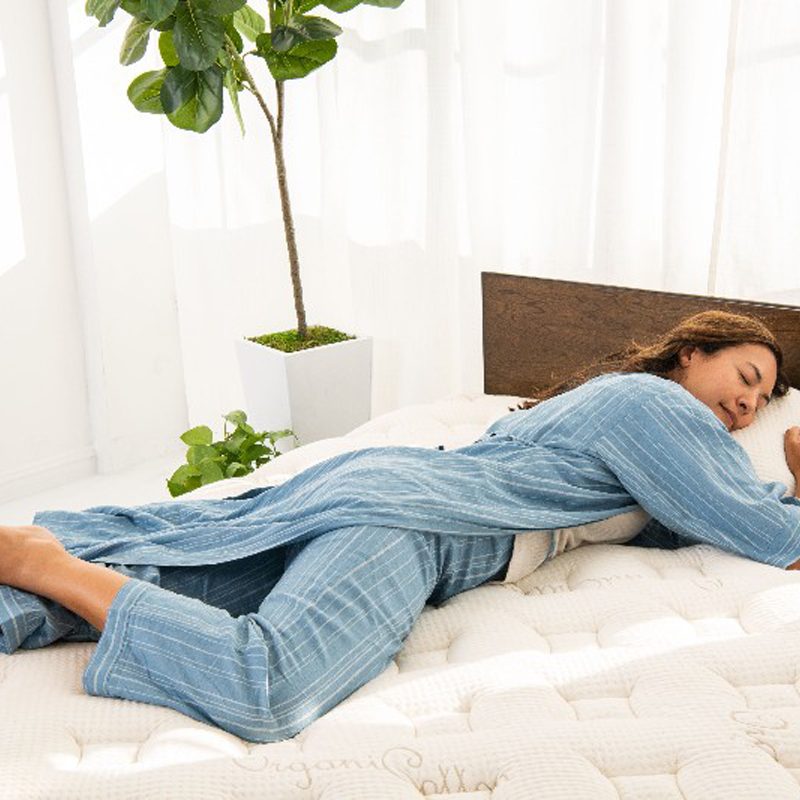 Woman sleeping on a Finch mattress with potted plants in the background.