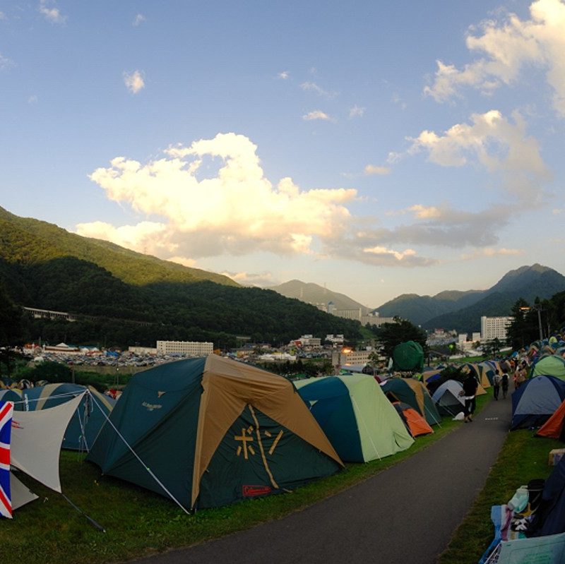 Campers from around the world gather peacefully in tents gather below green hills at Fuji Fest, 2007.
