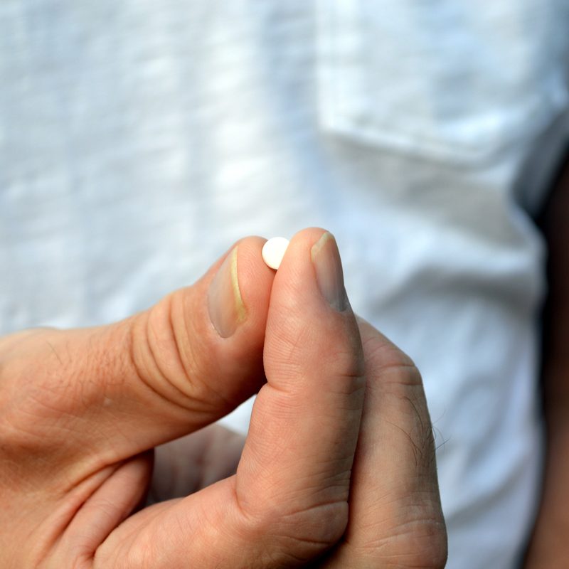 Man holding a small white pill
