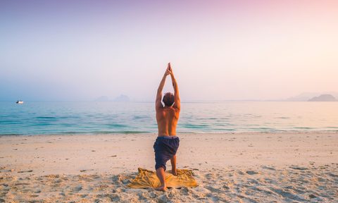 Man practicing yoga on the beach