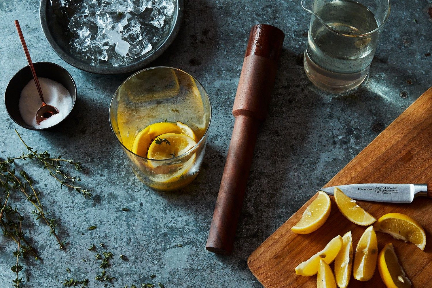 wooden muddler sitting on a table surrounded by garnishes and cocktails.