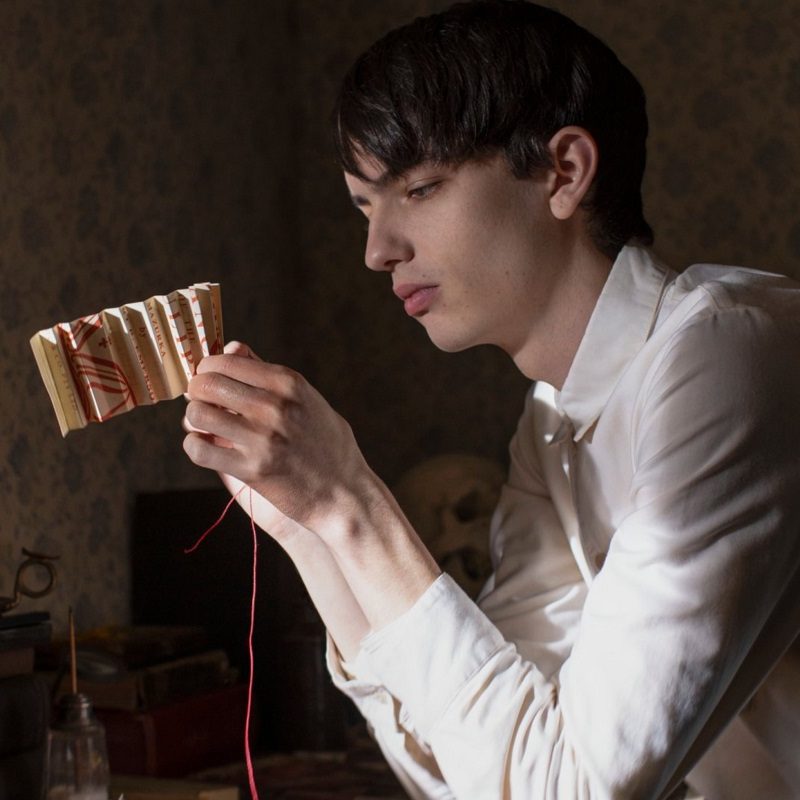 Kodi Smit-McPhee holding a folded paper in The Power of the Dog.