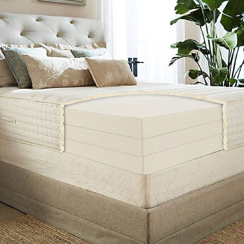 A latex foam mattress on a bed with potted plants in a bedroom.