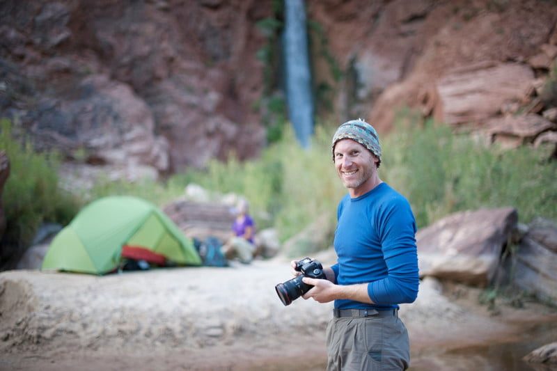 Man holding camera at a campsite - expedition expert Cameron L. Martindell