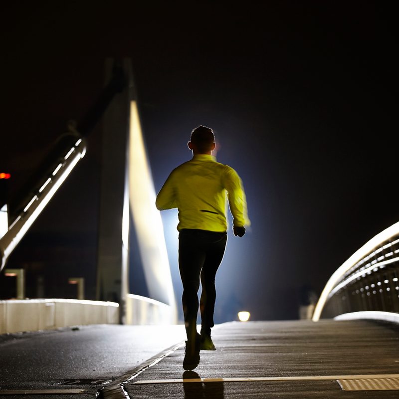 Rear view of a a man running at night time.