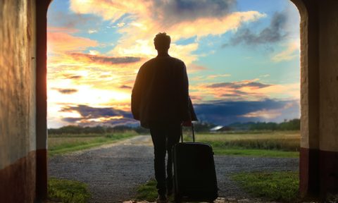 A man traveling with a suitcase that's filled with the best travel gear because he read this list.