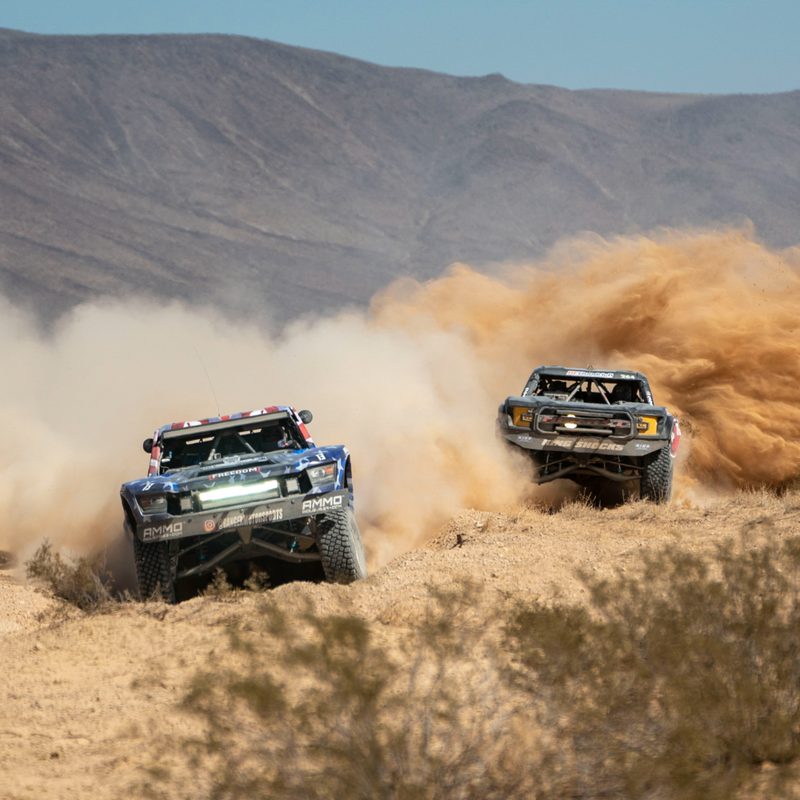 Unlimited class trucks coming through a turn in the Mint 400 race.