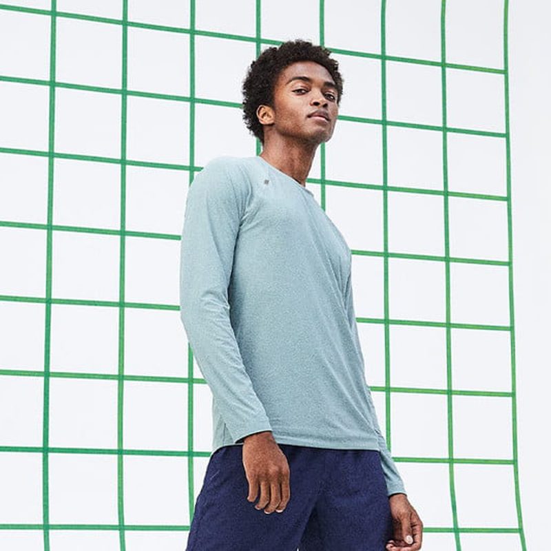 A man in blue long-sleeved shirt posing against a white backdrop with green grids.