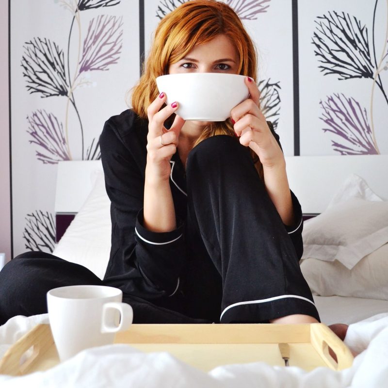 A woman drinks tea in bed
