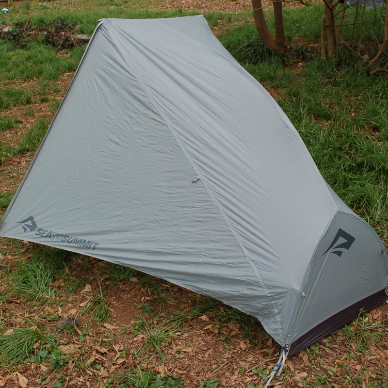 One-person backpacking tent with the rainfly staked out.