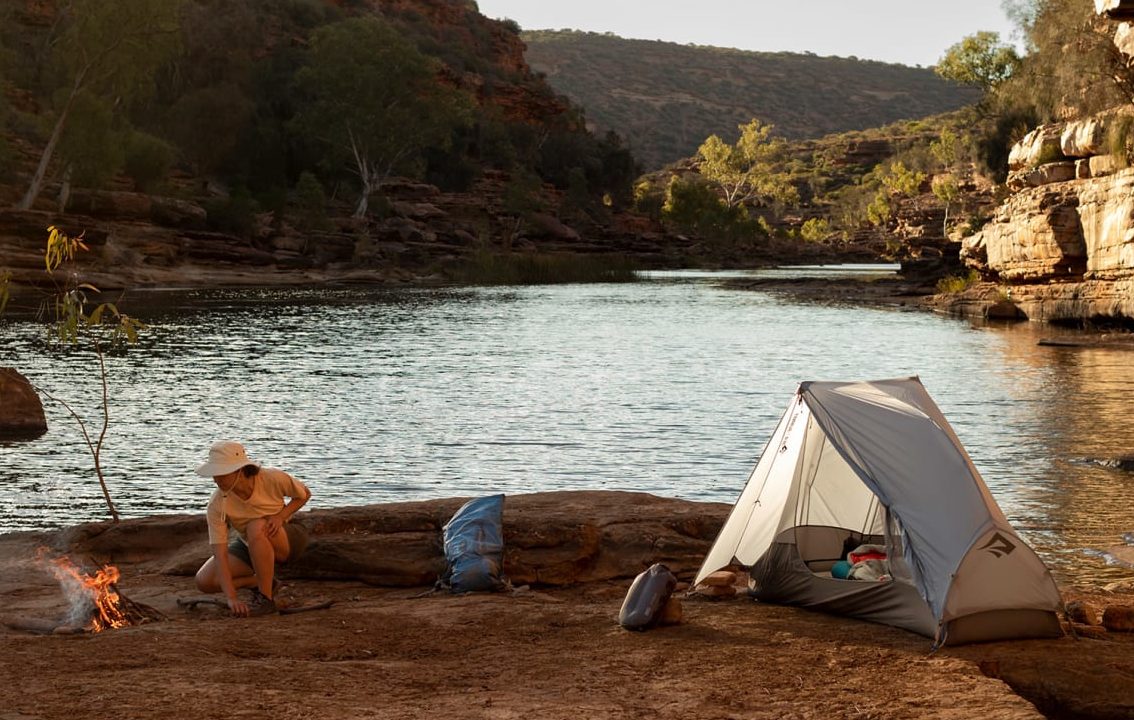 Person camping on a river using a one person tent