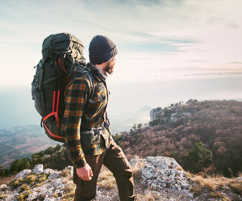 A hiker standing atop a mountain and looking out over the landscape