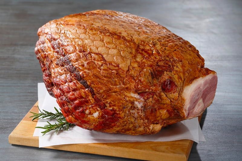 Snake River Farms Kurobuta Whole Bone-in Ham, which is laying on a cutting board.