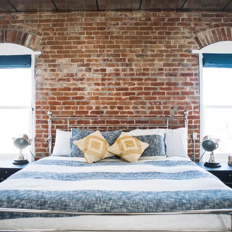 Exposed brick and twin windows above a bed at The Mill House boutique hotel in Lander, Wyoming.