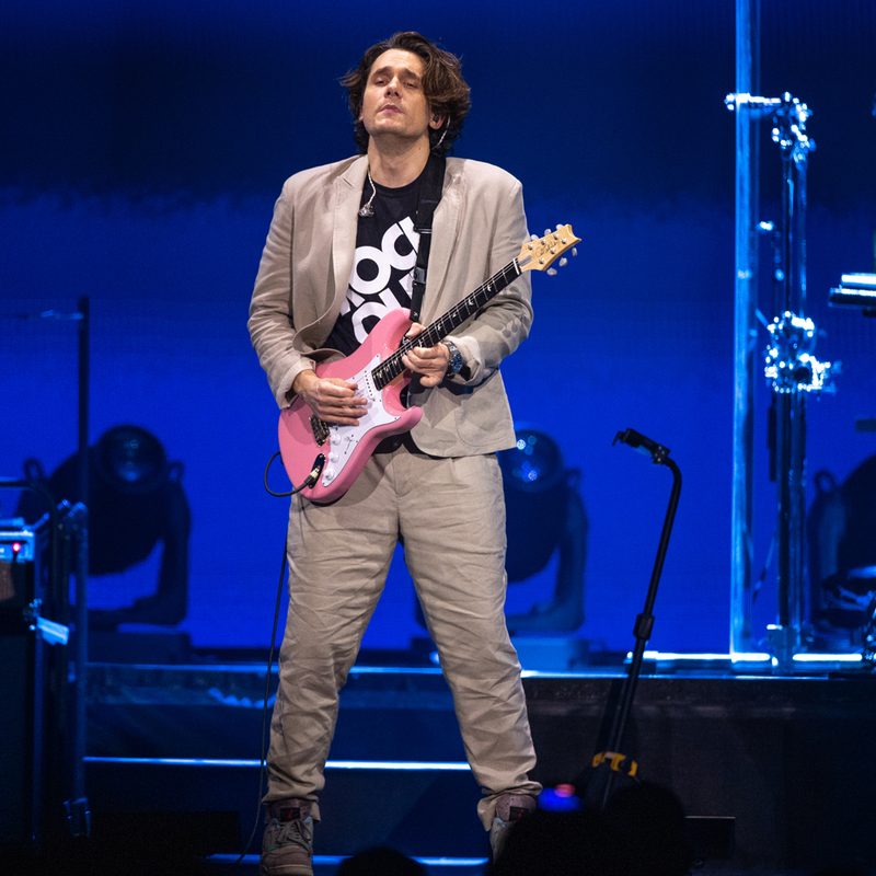 John Mayer strumming his guitar as he performs onstage at The Forum.