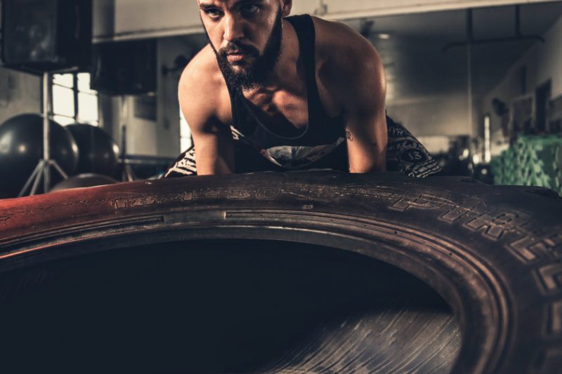Man flipping a tire while working out.