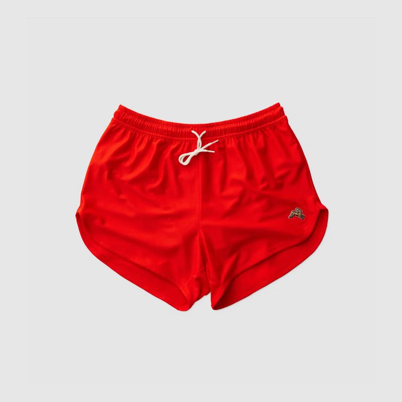 A pair of red Tracksmith Van Cortlandt Shorts on gray background.