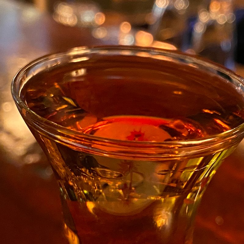 A close-up of a glass of genever in a bar.