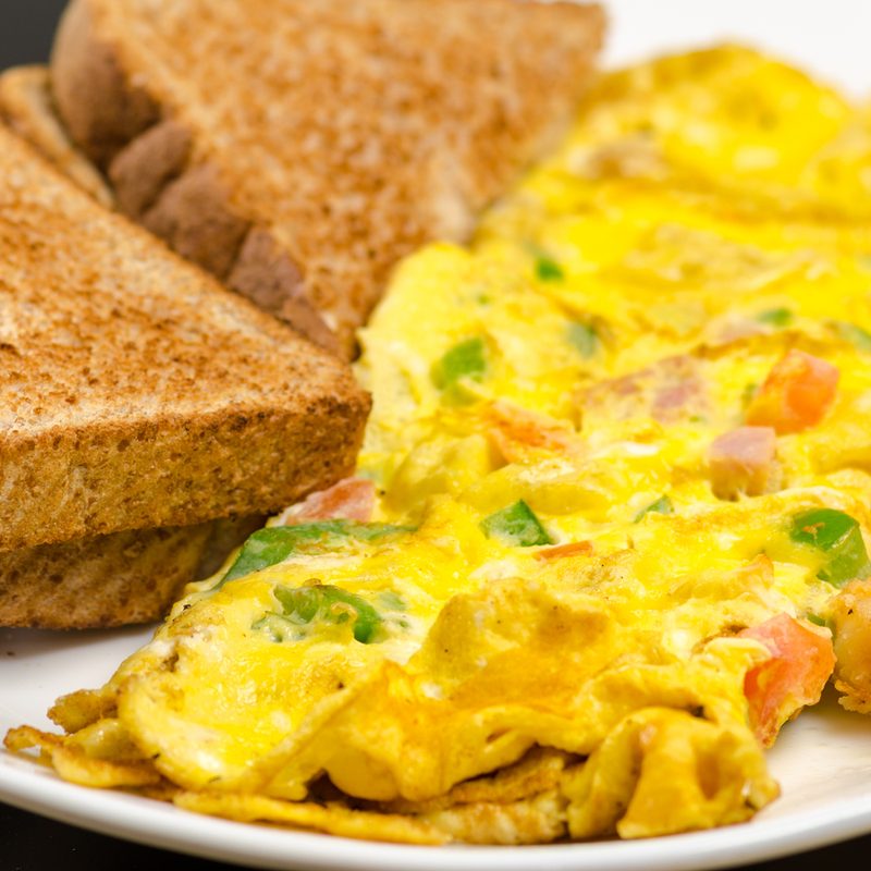 A veggie omelet beside toasted sandwiches on a plate.