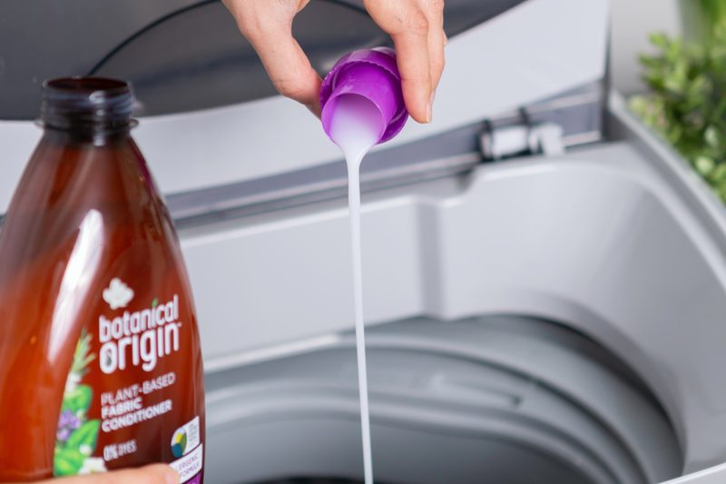 person pouring laundry detergent into a washing machine.
