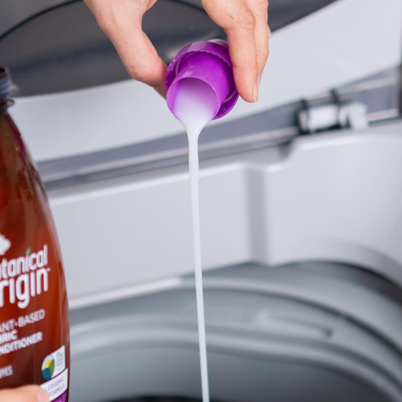 person pouring laundry detergent into a washing machine. 