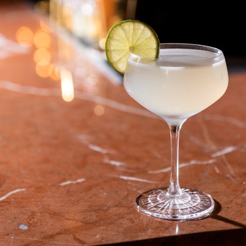 A White Flower cocktail garnished with lime on a table