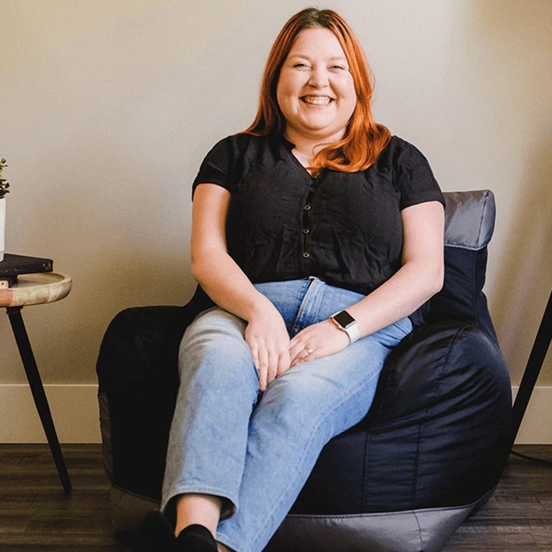 A woman sits on a Big Joe Dorm bean bag chair.