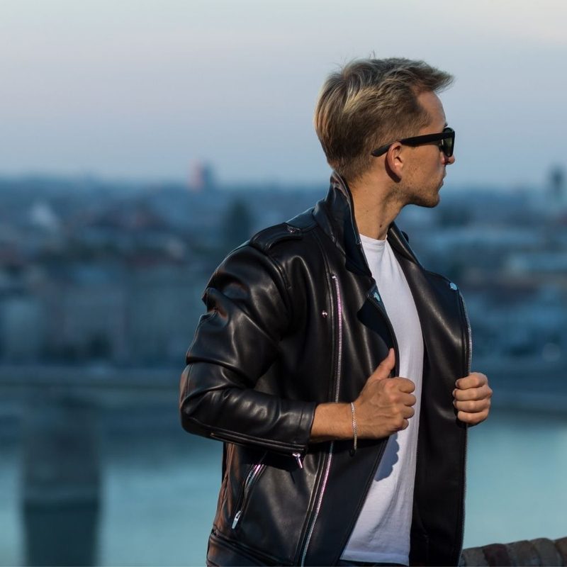 Man in leather jacket with cityscape in background