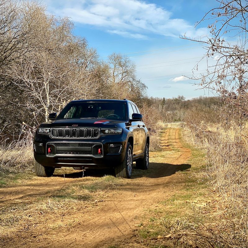 Front end of 2022 Jeep Grand Cherokee Trailhawk on a dirt trail.