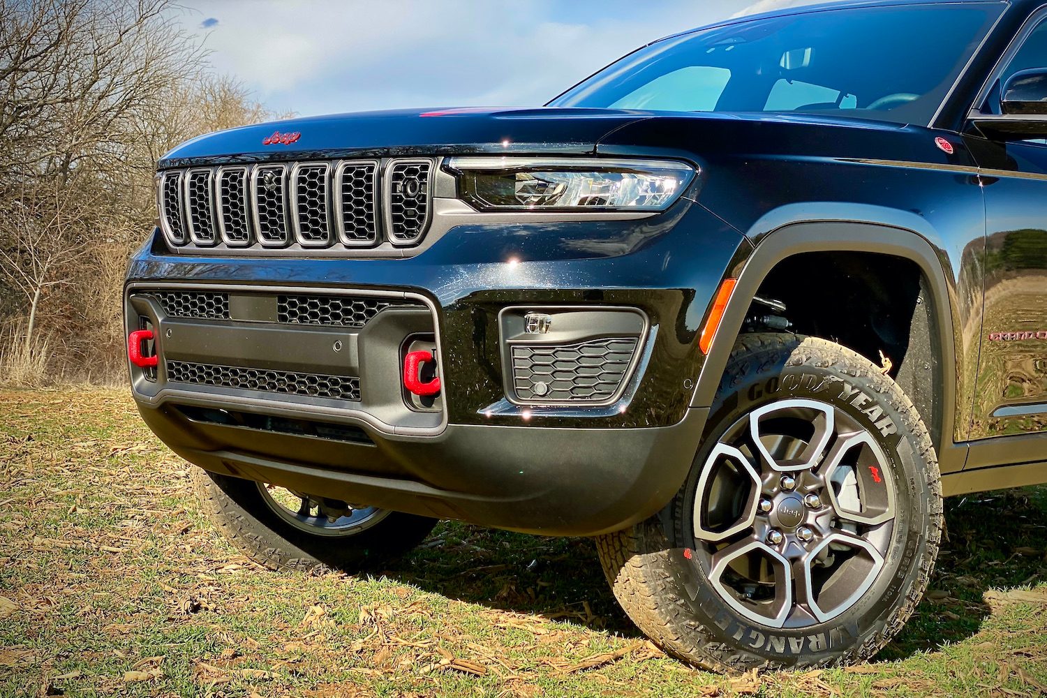 Front end of 2022 Jeep Grand Cherokee Trailhawk from driver's side with trees in the background.