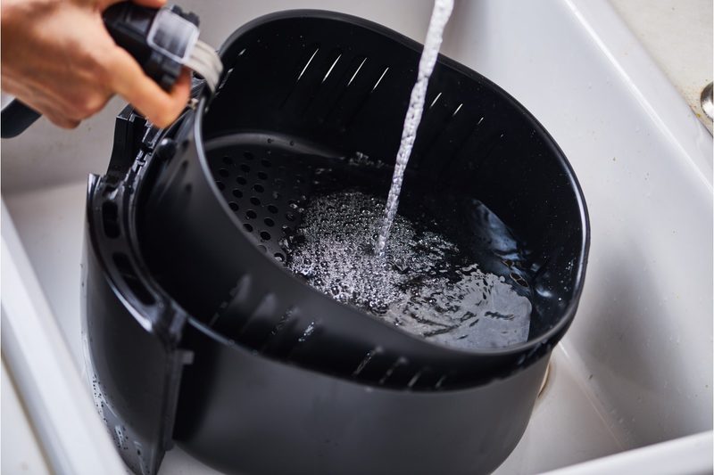 Water runs over the basket of an air fryer
