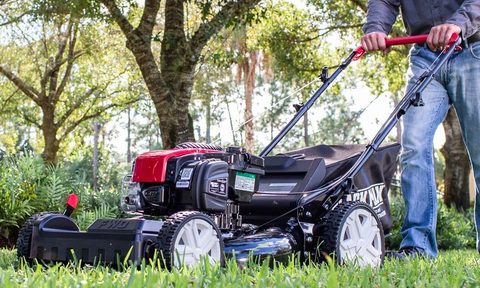 A man mows his lawn with the Black Max self-propelled lawn mower.