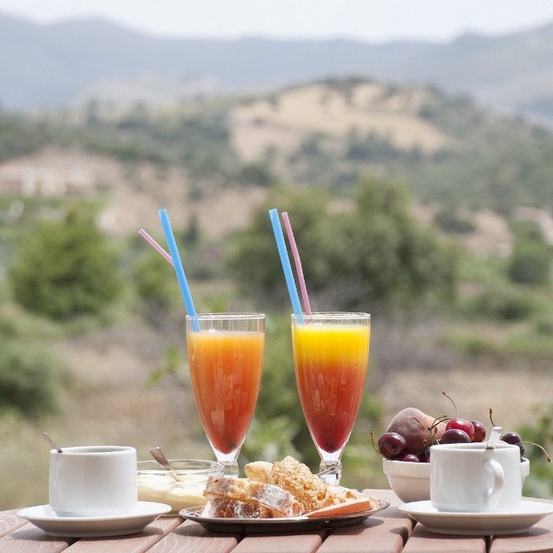 An outdoor breakfast spread that includes a pair of orange juices mixed with coffee.
