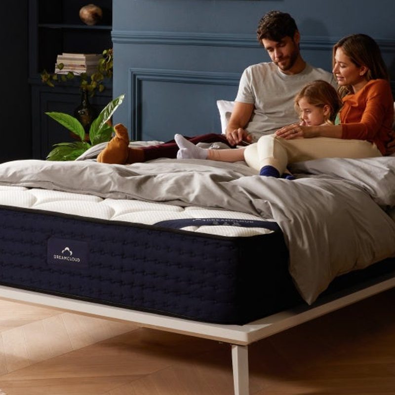 A family sits on the DreamCloud - Luxury Hybrid Mattress in the bedroom