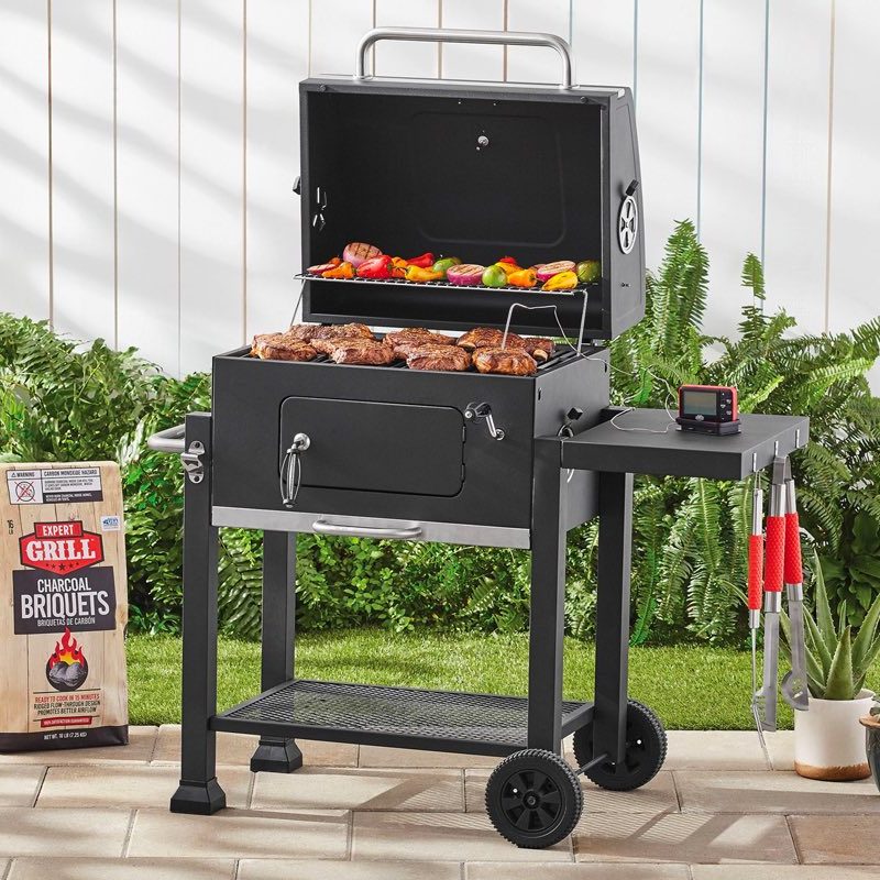 The Expert Grill charcoal grill sits on a patio next to a bag of charcoal.