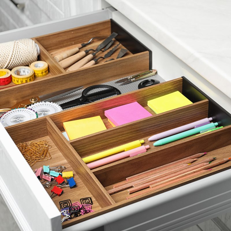 Different stationery in open desk drawer indoors.