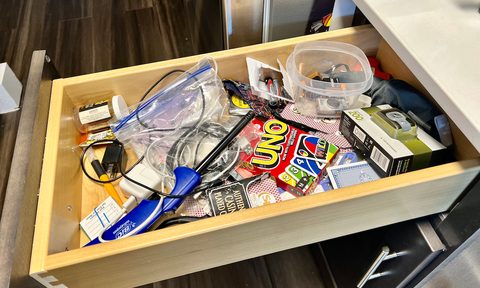 An open kitchen junk drawer filled with assorted home items.