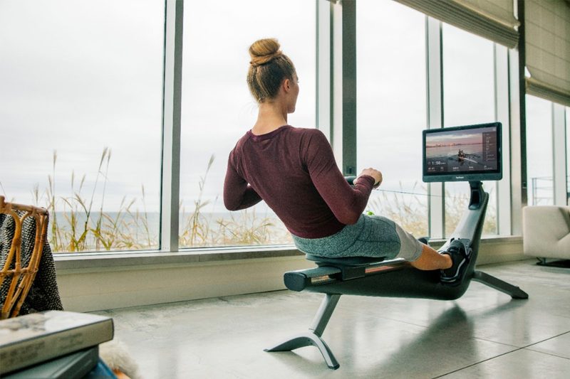 A woman does rowing exercises on her Hydrow Connected Rower.