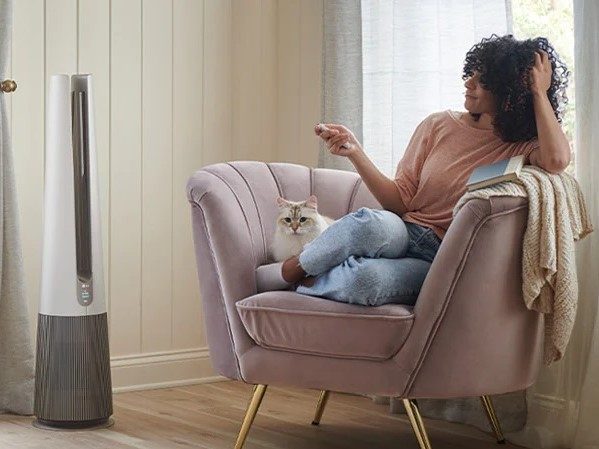 Woman controlling LG PuriCare AeroTower remotely.
