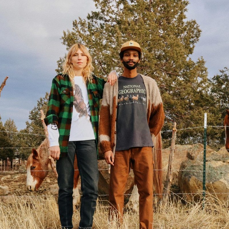 Models wear National Geographic and Parks Project T-shirts while standing in front of horses.