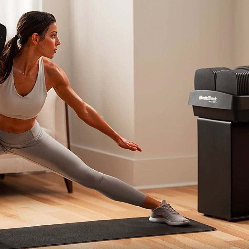 A woman works out with the NordicTrack iSelect adjustable dumbbells.