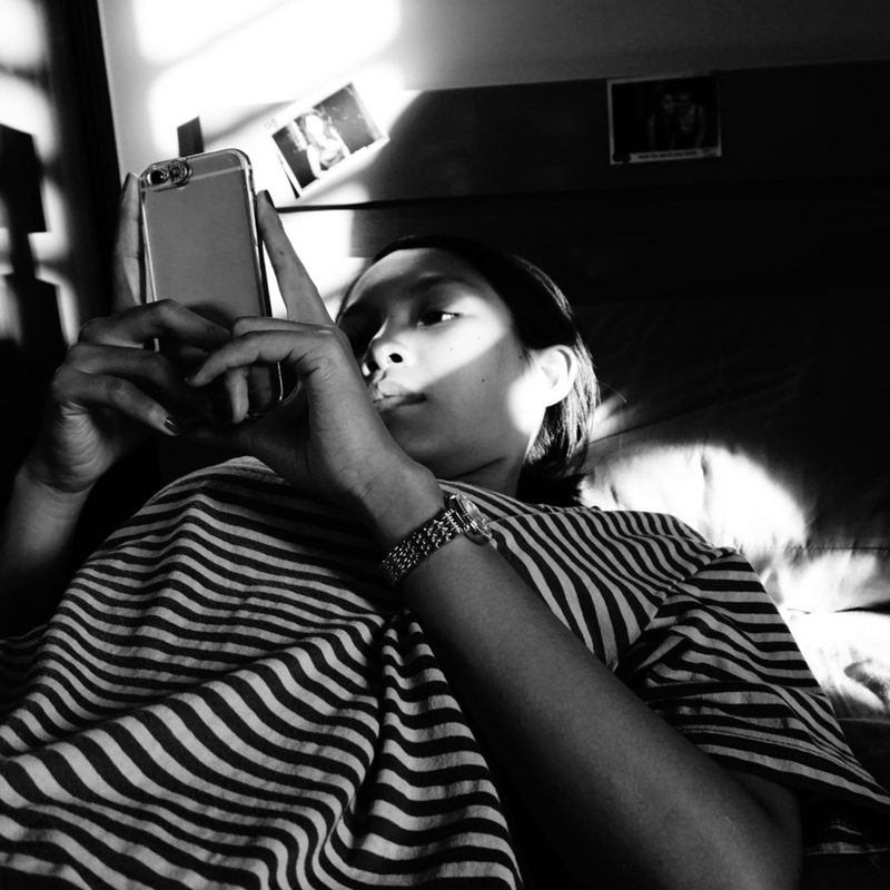 A woman uses her smartphone while lying in bed