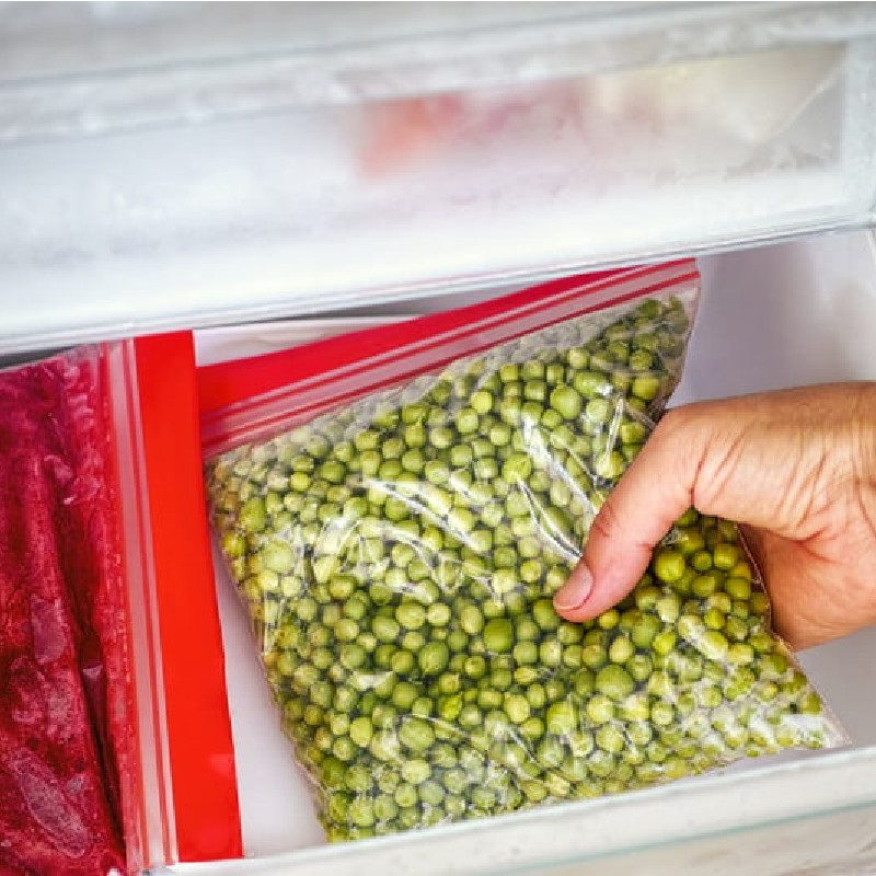 Person placing bagged vegetables into the freezer