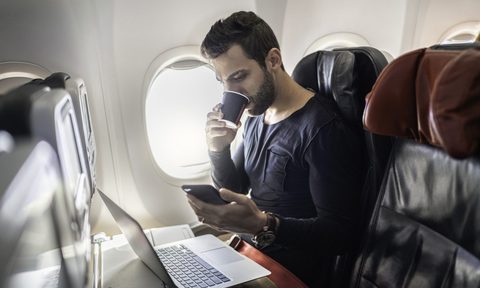 A person on a plane on their laptop and phone