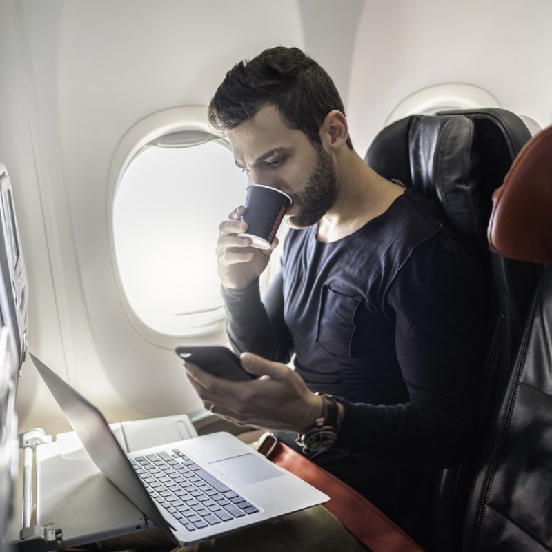 A person on a plane on their laptop and phone