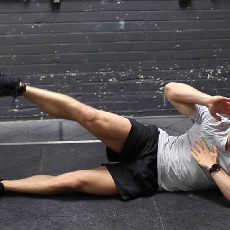 Man performing a side-jack knife on a rubber mat.