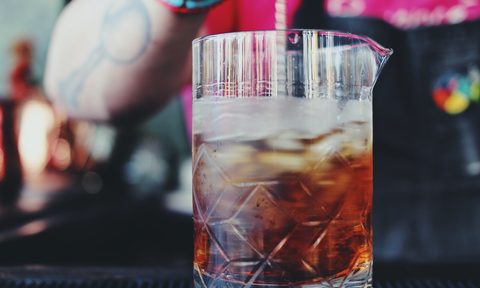 A bartender stirs a cocktail in a mixing glass.