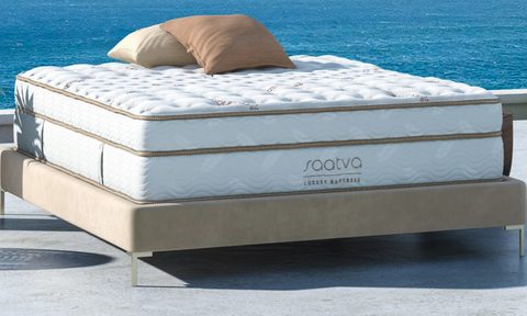 A Saatva Classic mattress lies on a patio facing the ocean.